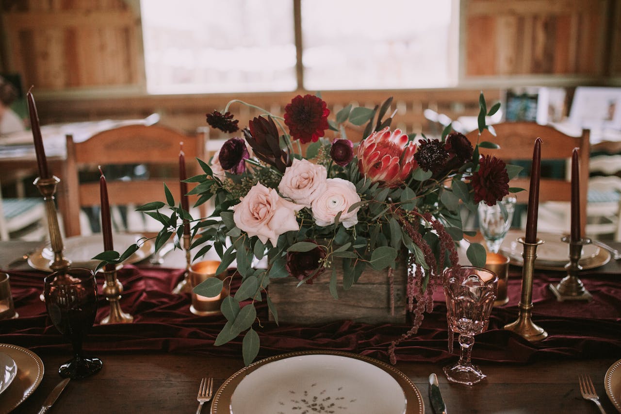 A beautifully arranged floral centerpiece at a wedding reception with elegant tableware and decor.